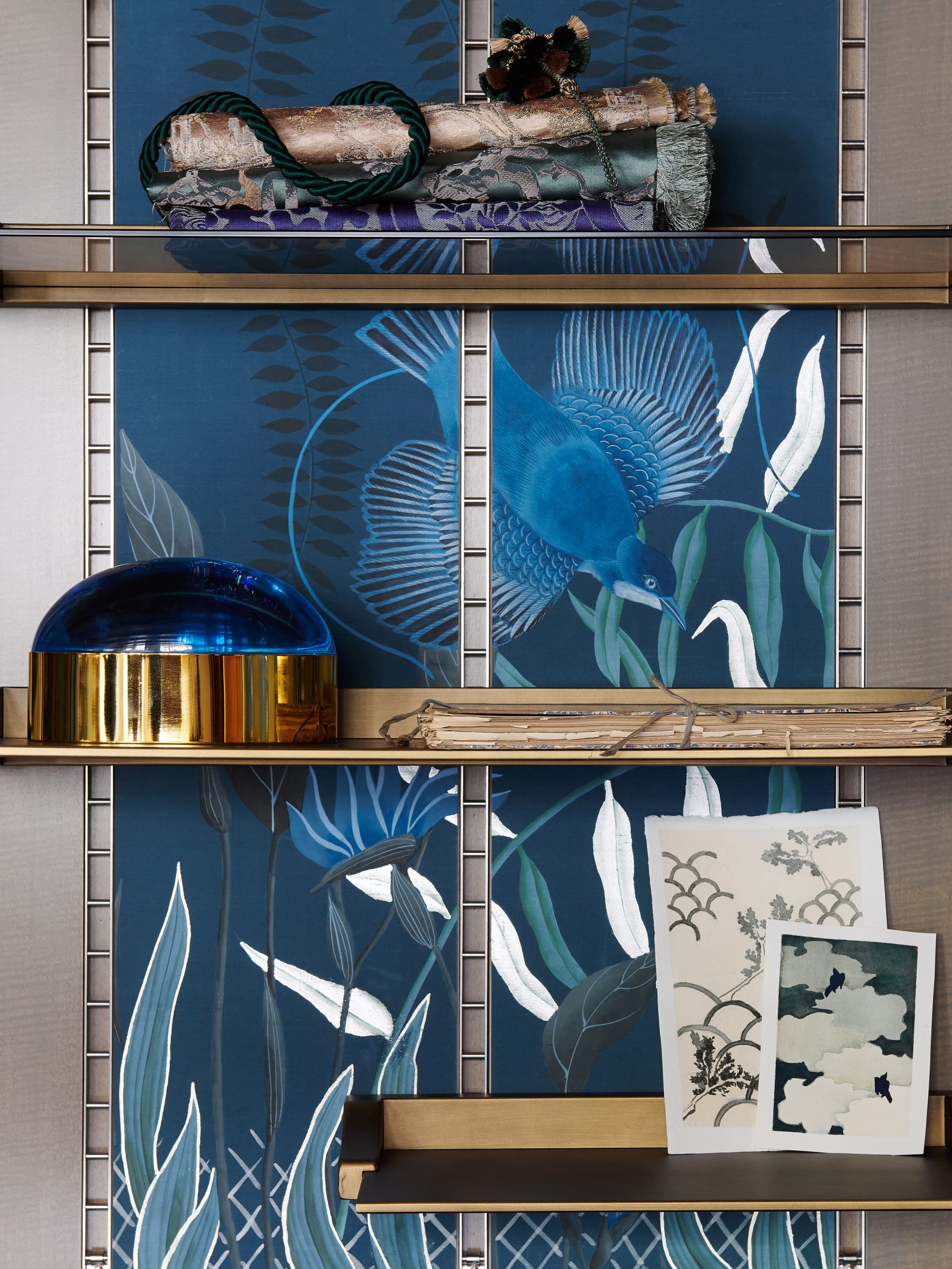 A hand-painted blue bird panel surrounded by textiles, drawings and studio objects